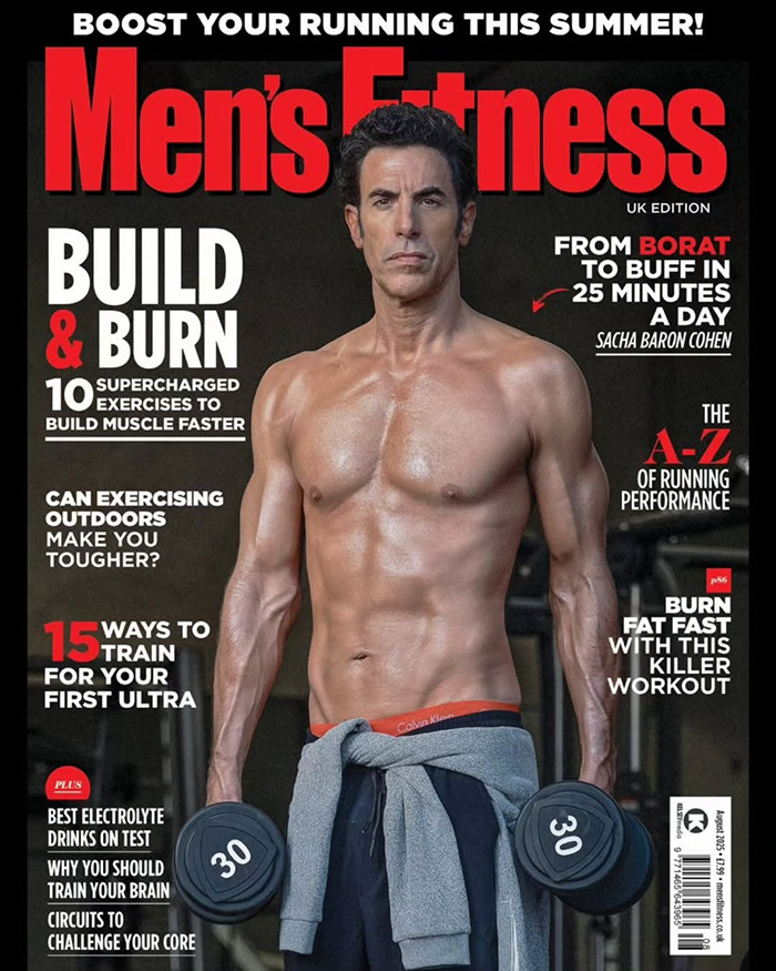 Sacha Baron sin camisa Cohen sosteniendo pesas en la cubierta de fitness de los hombres que muestra la transformación del cuerpo de Marvel y las puntas de la construcción muscular.