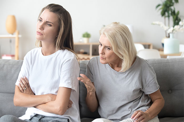 Pareja sentada en el sofá en una conversación tensa, ilustrando la terapia de esposa de marido después de 19 años de problemas matrimoniales.