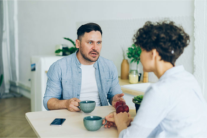 Pareja en la sesión de terapia en el hogar discutiendo temas después de la sorpresa de cumpleaños del esposo para la esposa causa tensión.
