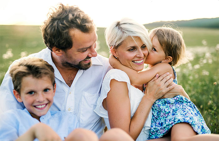 Feliz familia al aire libre con esposo, esposa e hijos que comparten un momento después de las discusiones de la terapia matrimonial.