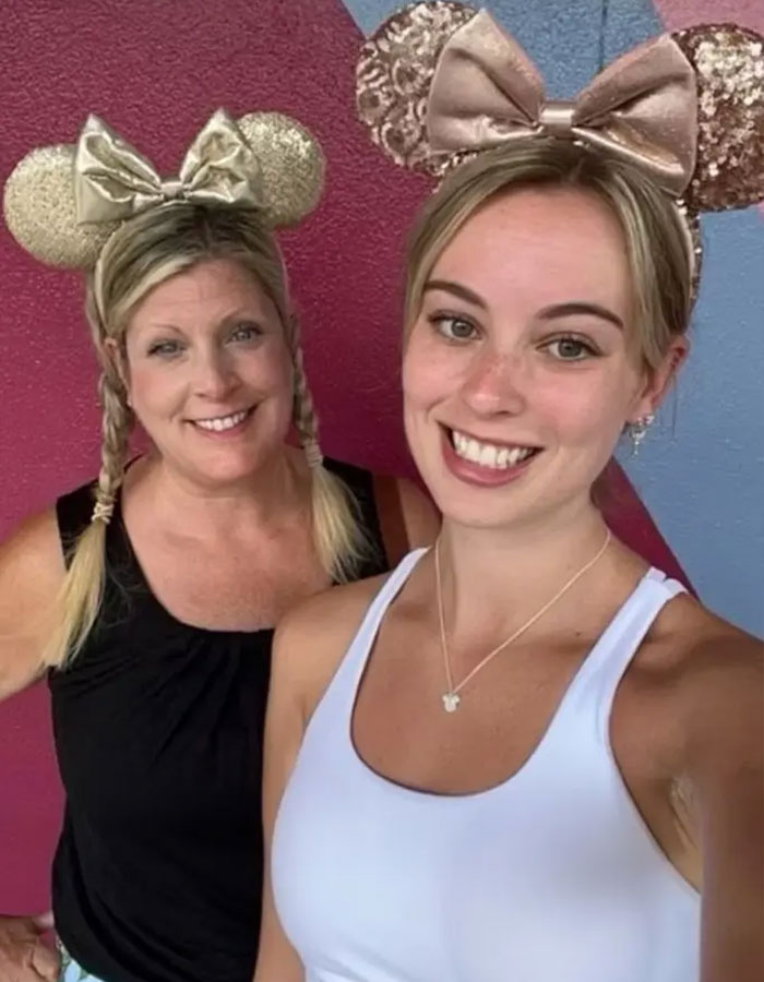 Dos mujeres que usan orejas de ratón Minnie brillantes sonriendo a la cámara, relacionadas con el giro de incidentes de Disney World.