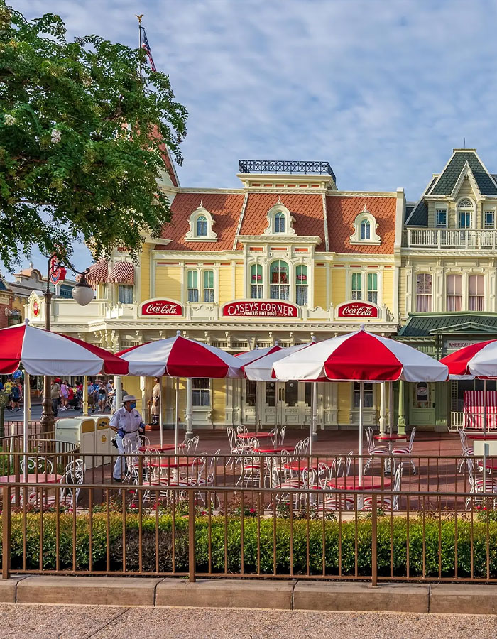 Asientos al aire libre con paraguas rojos y blancos en Casey's Corner en Disney World, vinculados a las violentas palabras clave de los incidentes de Disney World.