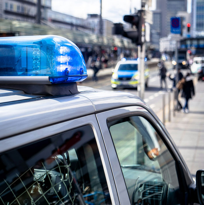 Vehículo policial con luces azules estacionadas en City Street, relacionado con compañeros de cuarto que se niegan a devolver el CA y el caso de actividades ilegales.