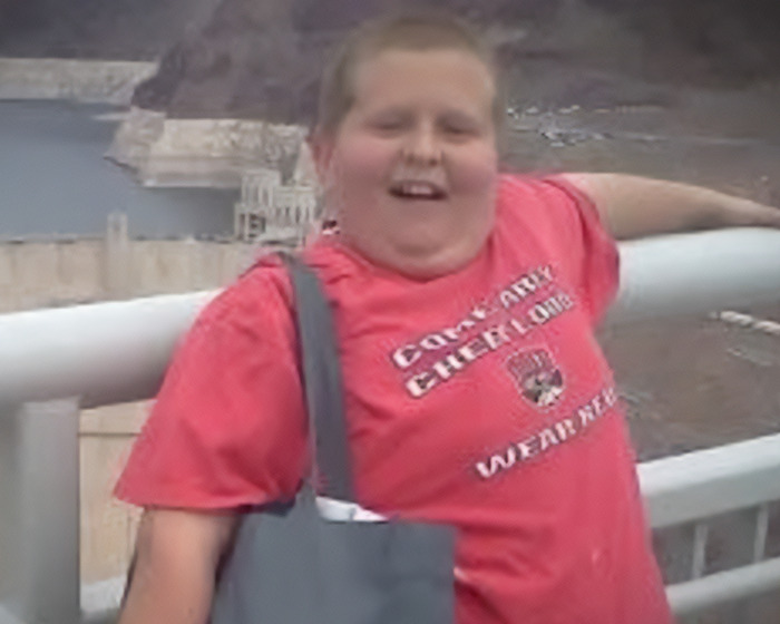 Young Man con camisa roja sonriendo al aire libre, relacionada con la historia sobre las acusaciones biológicas del padre y la familia del hermano.