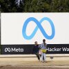 La gente habla cerca de un meta signo fuera de la sede de la compañía en Menlo Park, California, el 7 de marzo de 2023. (AP Photo/Jeff Chiu)