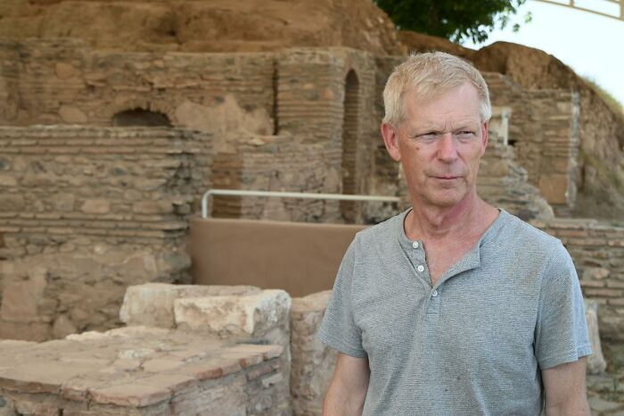 Hombre de mediana edad de pie cerca de las antiguas ruinas de piedra de un sitio del palacio lidio en el oeste de Türkiye Excavación arqueológica.