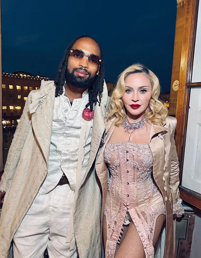 Madonna con su novio de 29 años por la noche, ambos vestidos con elegantes atuendos de inspiración vintage al aire libre.