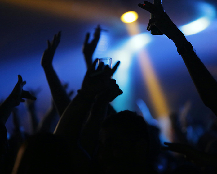 Siluetas de personas que levantan las manos y las bebidas en un entorno de club oscuro, relacionadas con la advertencia de la mujer después del rescate.