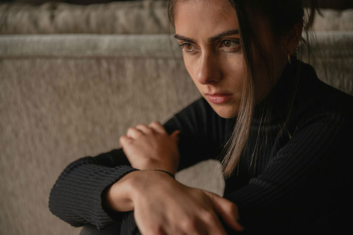 Mujer claustrofóbica sentada sola con una angustia y molesta después de que la broma de un marido llegue demasiado lejos.