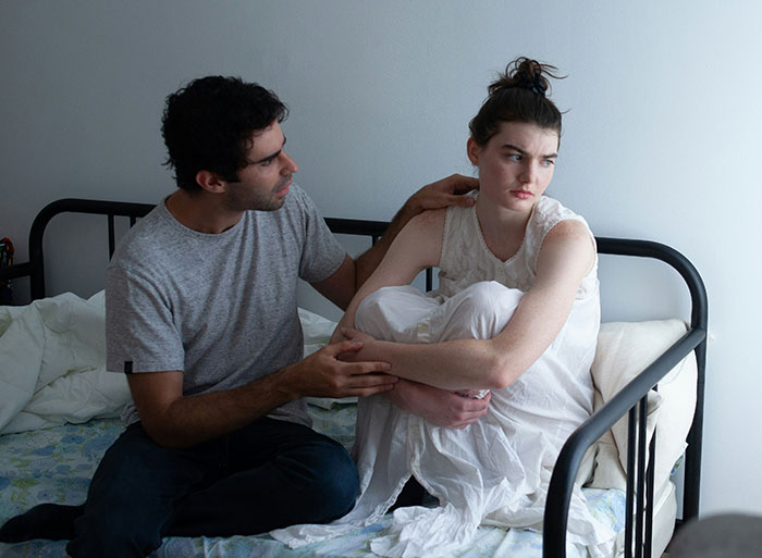 Pareja que tiene una conversación tensa en la cama, una mujer molesta cuando su novio acepta cortar el césped de su ex y se queja en línea.