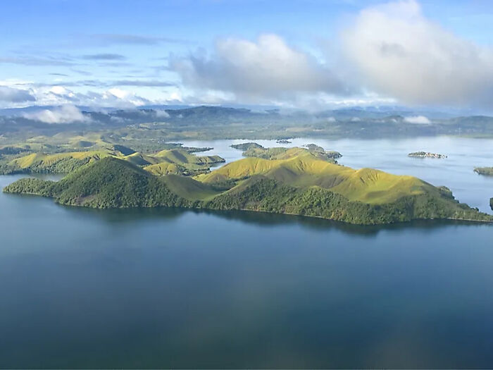 Vista aérea de las exuberantes islas verdes rodeadas de agua tranquila, relacionada con la influencia, las chispas de indignación, filmando a la tribu indígena.