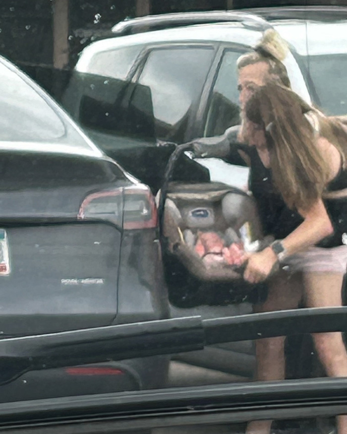 Dos mujeres fuera de un automóvil, una sosteniendo un portabebés, provocando especulaciones sobre la maternidad y el matrimonio de Hensel Twins.