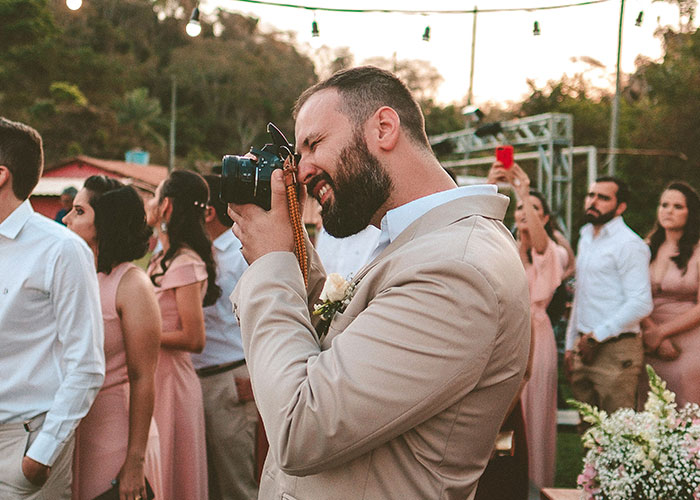 Man in Beige Suit tomando fotos en una boda, destacando la crítica del costoso servicio de fotógrafos de bodas.