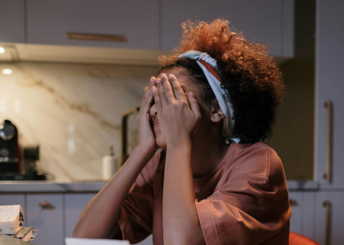 Mujer que se ve estresada en la cocina, considerando encerrar la comida debido al molesto comportamiento de los suegros baratos.