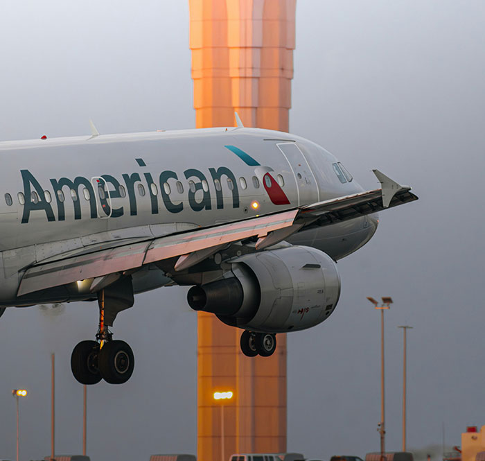 American Airlines Airplane Landing cerca de la Torre del Aeropuerto, que ilustra los problemas de discriminación de los senos y la azafata.