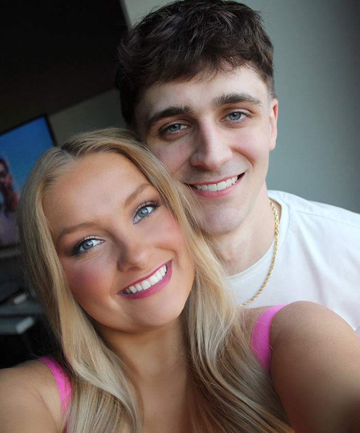 Pareja joven sonriendo juntas en un entorno informal, relacionados con las publicaciones en las redes sociales sobre la maternidad y la historia oculta del cuerpo del bebé.