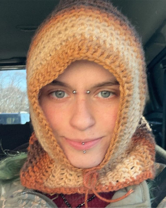 Primer plano de la novia peluda sospechosa de Minneapolis con una capucha con piercings faciales dentro de un vehículo.