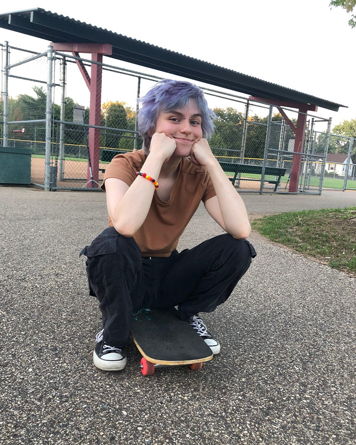 Persona joven con cabello morado sentado en una patineta en un parque, vinculado a Minneapolis sospechoso de la novia Furry Girlfriend Report