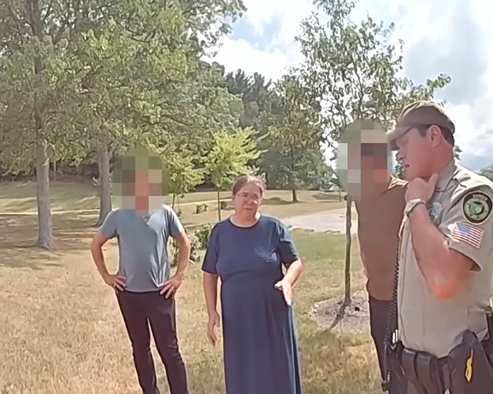 Mamá Amish hablando con oficiales al aire libre en un parque en una confesión escalofriante después de un incidente ahogado.