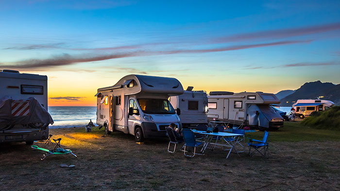 Campers y RV estacionados en la playa al atardecer, simbolizando un viaje mundial de 7 años y una reunión familiar.