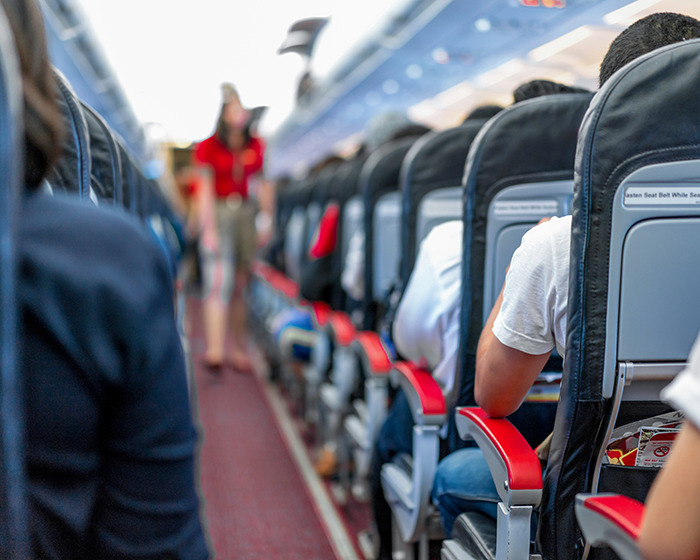 Los pasajeros se sentaron dentro de una cabina de avión con asientos reclinados, ilustrando problemas de espacio e incomodidad de pasajeros.
