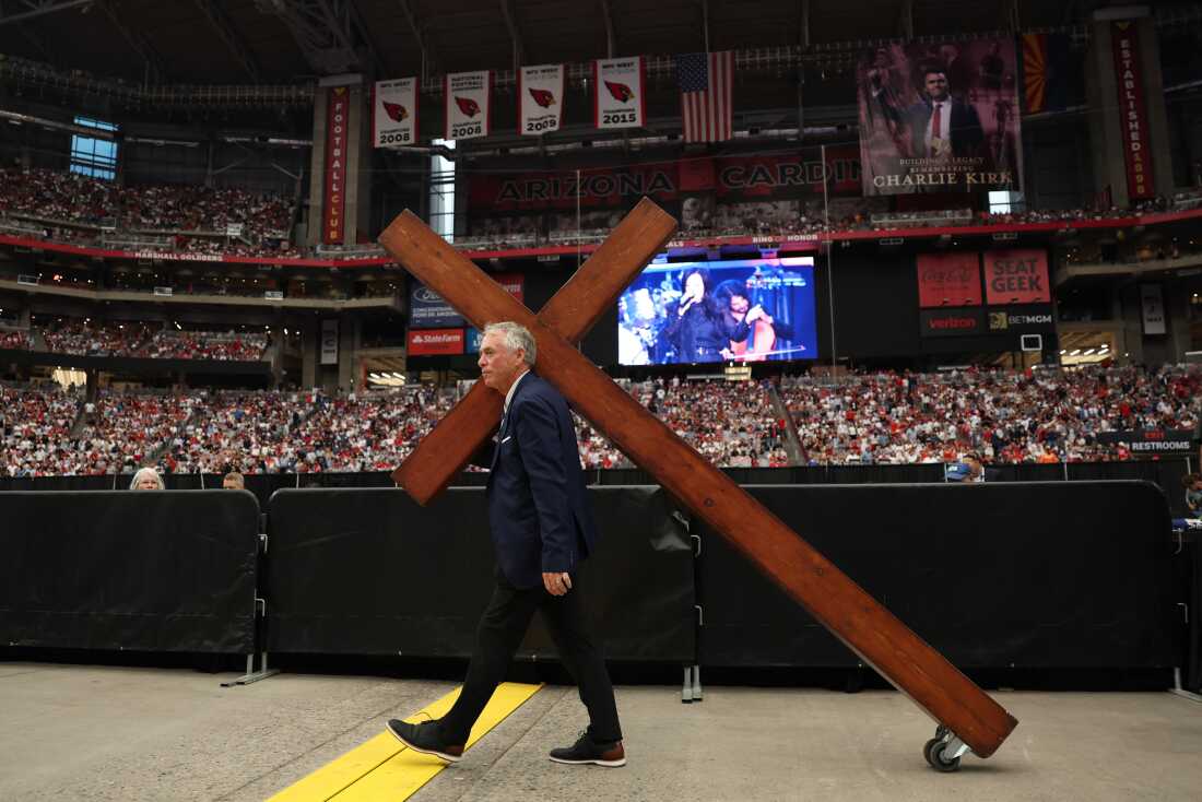 Se lleva una gran cruz por delante del Servicio Memorial Público para el activista de derecha Charlie Kirk en el Estadio State Farm en Glendale, Arizona, el 21 de septiembre de 2025. (Foto de Patrick T. Fallon / AFP) (Foto de Patrick T. Fallon / AFP a través de imágenes de Getty)