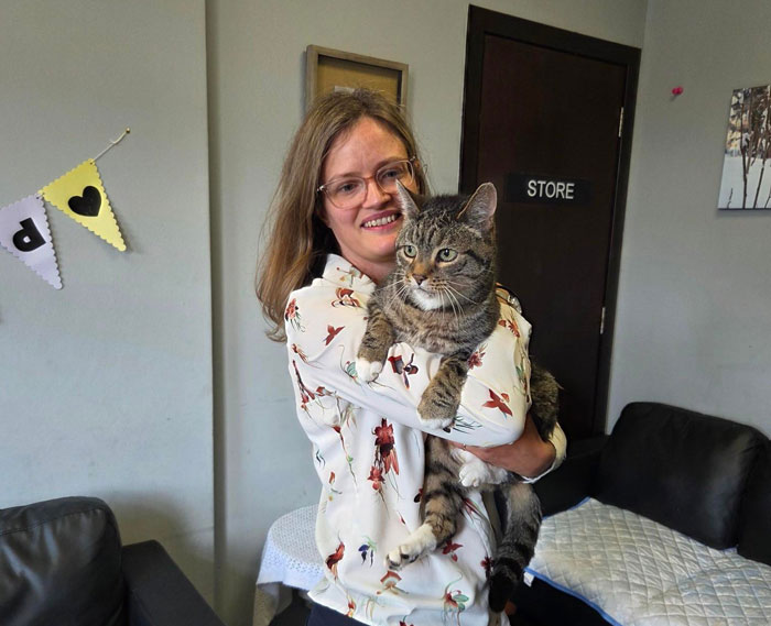 Mujer sosteniendo un gato atigrado en el interior, feliz familia reunida con el amado gato después de casi una década con vida y bien.