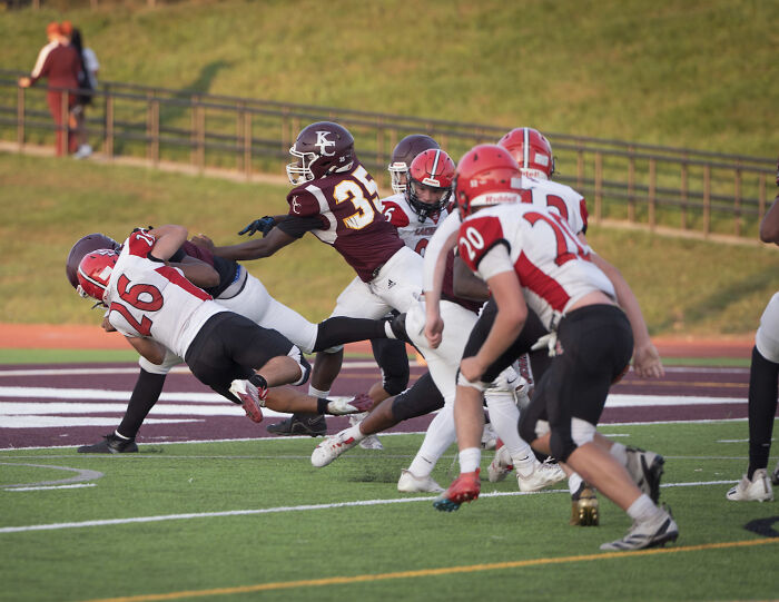 Jugadores de fútbol de la escuela secundaria en acción en el campo durante una respuesta escolar fuerte y decisiva al incidente de lesiones.