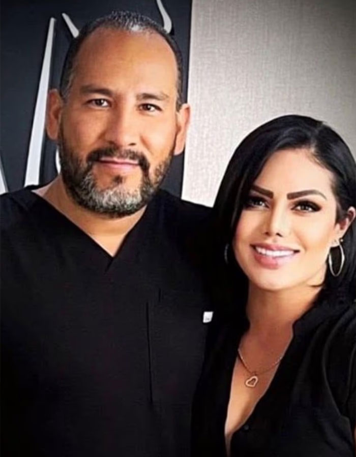 Cirujano que realizó un agrandamiento fatal de senos y la madre de la adolescente posando juntos, ambos vestidos con negro en el interior.