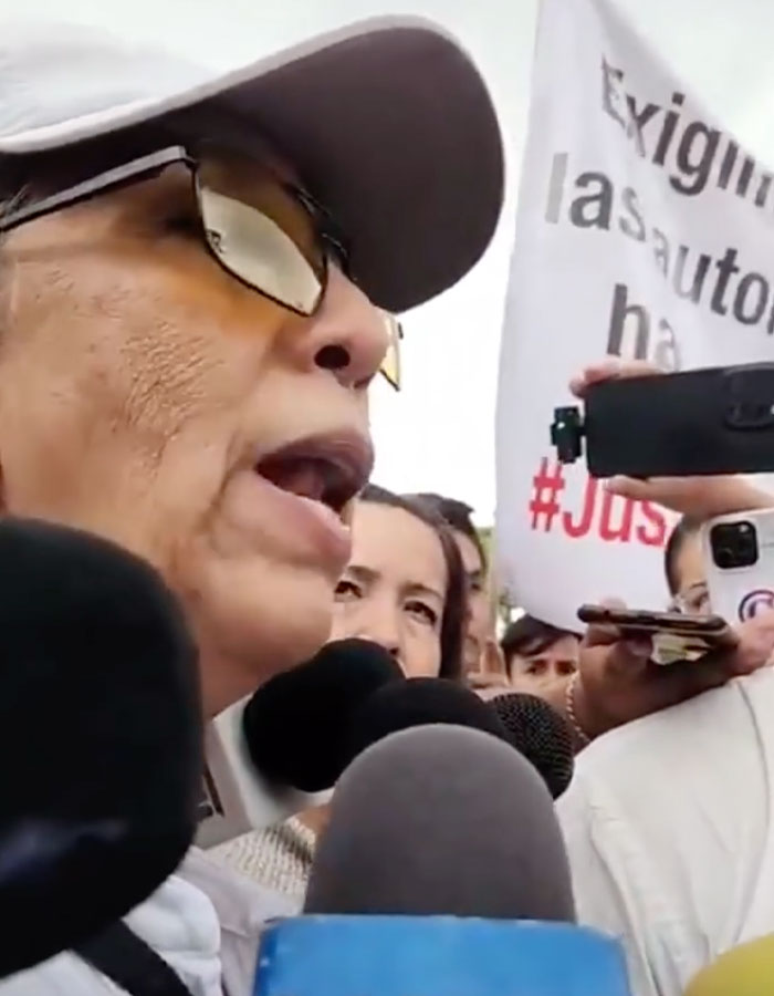 Mujer que habla con los periodistas durante una protesta relacionada con el cirujano detenido después de la agrandamiento fatal de los senos sobre el adolescente.