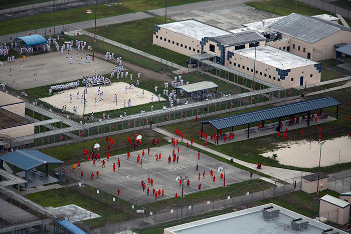 Vista aérea de los detenidos en un patio del centro de detención de hielo con cercas y múltiples áreas de recreación visibles.