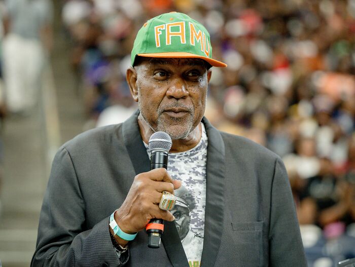 El locutor de la banda de la universidad que habla en el micrófono en el evento, vinculado a bailarines de talla grande y disculpas de bordes.