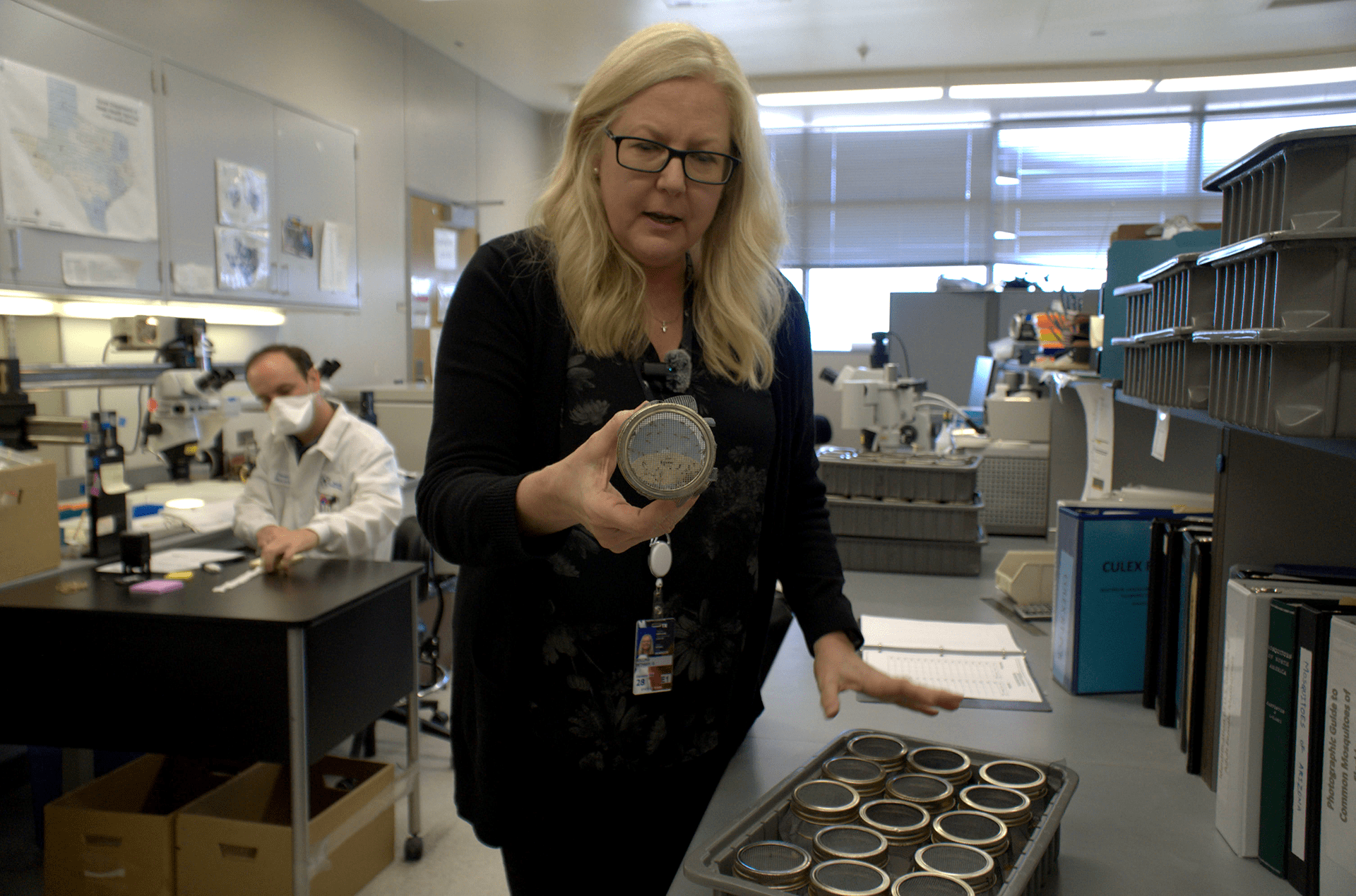 A woman holds a round container up to the camera.
