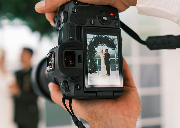 Primer plano de una pantalla de cámara que muestra una foto de boda, ya que una mujer considera recrear fotos de bodas debido a los malos originales.