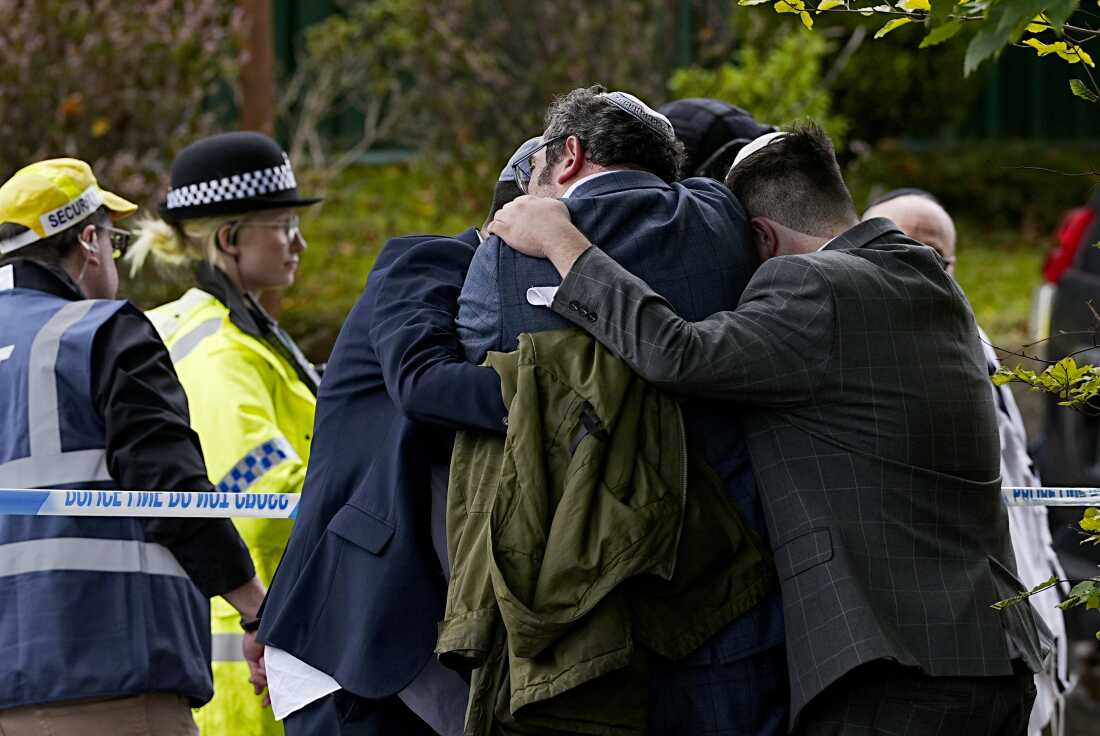 Los miembros de la comunidad judía se consolan entre sí cerca de la sinagoga de la Congregación Hebrea de Heaton Park en Crumpsall, Manchester, Inglaterra, donde dos personas murieron en un ataque el jueves que la policía calificó un incidente terrorista.