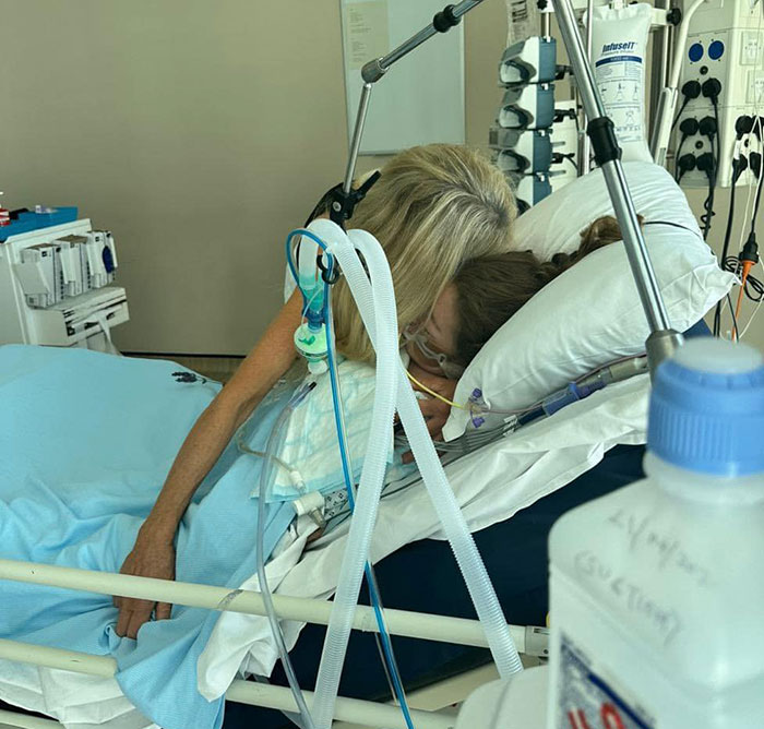 Mujer reconfortando a la hija en la cama del hospital con equipo médico, destacando al forense que revela la negativa del impacto de la quimioterapia.