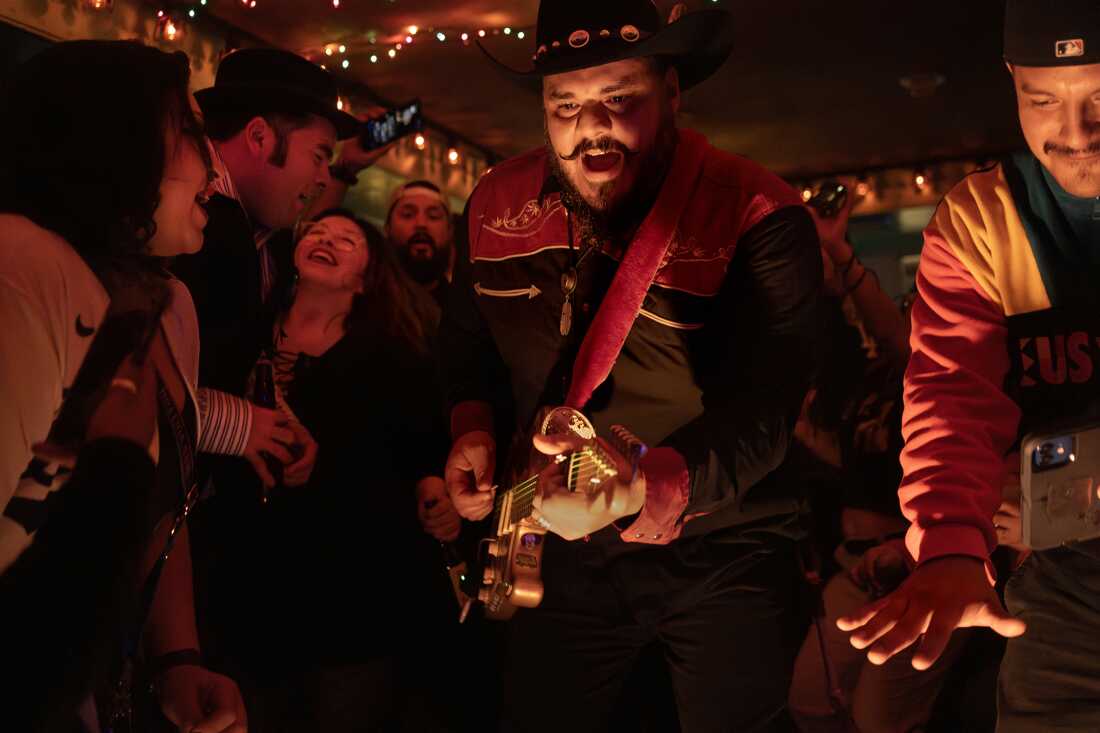 UNITED STATES, LA - Pedro Zapata, known as Pedro Pistolas, guitar player and vocalist in Spaghetti Cumbia, plays his guitar surrounded by the crowd at a show at Las Perlas in Los Angeles on March 30, 2023. The band Spaghetti Cumbia created their own sub-genre by combining cumbia with western styles and rock ’n roll. They grew up on the east side of Los Angeles when gang violence plagued the area; the members turned to music as an alternative path. Now, they rock clubs, while keeping day jobs to support their families. ESTADOS UNIDOS, LA - Pedro Zapata, conocido como Pedro Pistolas, guitarrista y vocalista de Spaghetti Cumbia, toca su guitarra rodeado por la multitud en un espectáculo en Las Perlas en Los Ángeles el 30 de marzo de 2023. La banda Spaghetti Cumbia creó su propia subgénero combinando la cumbia con estilos occidentales y rock 'n roll. Crecieron en el lado este de Los Ángeles cuando la violencia de las pandillas plagaba el área; Los miembros recurrieron a la música como un camino alternativo. Ahora, triunfan en los clubes del centro de Los Ángeles, mientras mantienen trabajos diarios para mantener a sus familias.