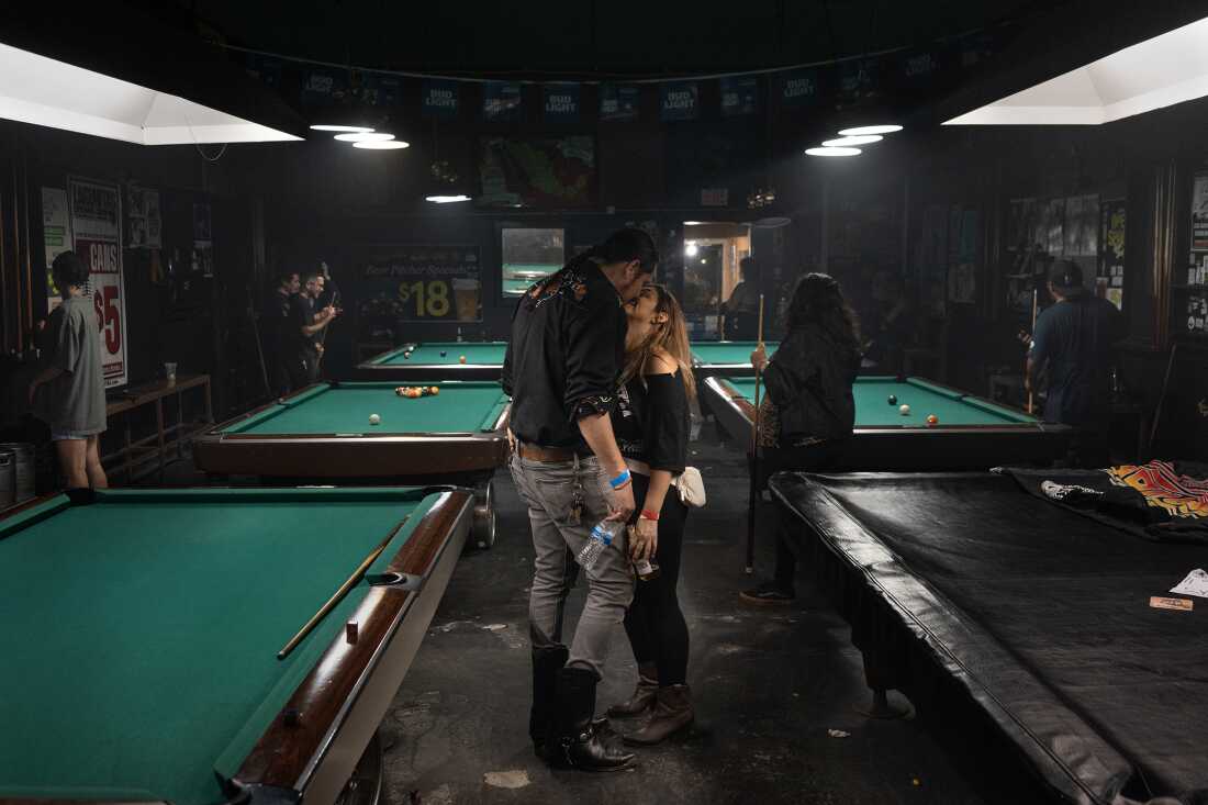 UNITED STATES, LA - Bobby Guerrero, known as El Gallo, guitar player of Spaghetti Cumbia, kisses his his girlfriend after a show at 1st street Pool & Billiard in Boyle Heights on June 18, 2023. The band Spaghetti Cumbia created their own sub-genre by combining cumbia with western styles and rock ’n roll. They grew up on the east side of Los Angeles when gang violence plagued the area; the members turned to music as an alternative path. Now, they rock clubs, while keeping day jobs to support their families.