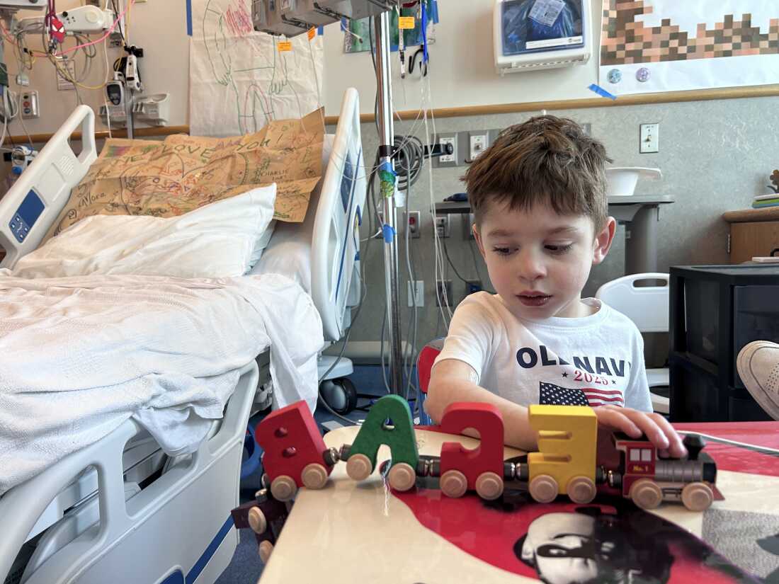 Caleb Strickland plays with a wooden toy train at the hospital.