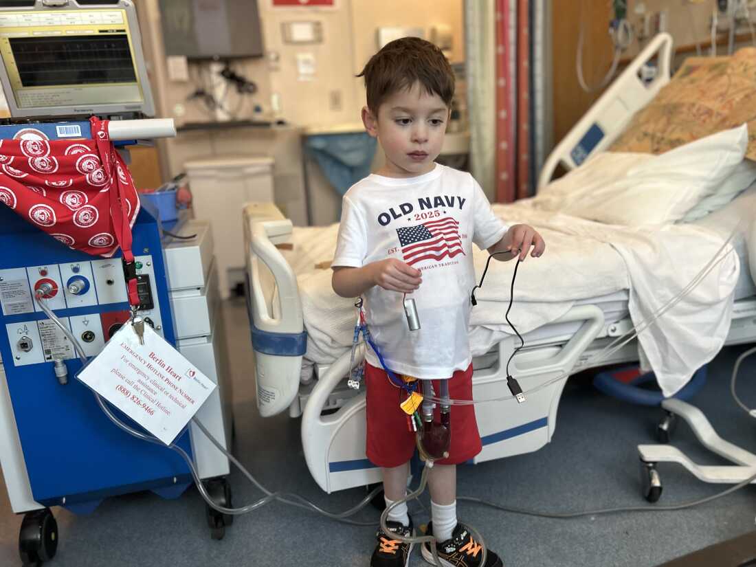 Caleb Strickland stands while tethered to his ventricular assist device.