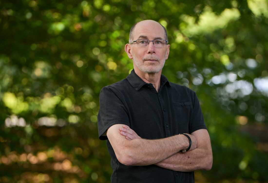 Ned Place stands outdoors with his arms crossed.