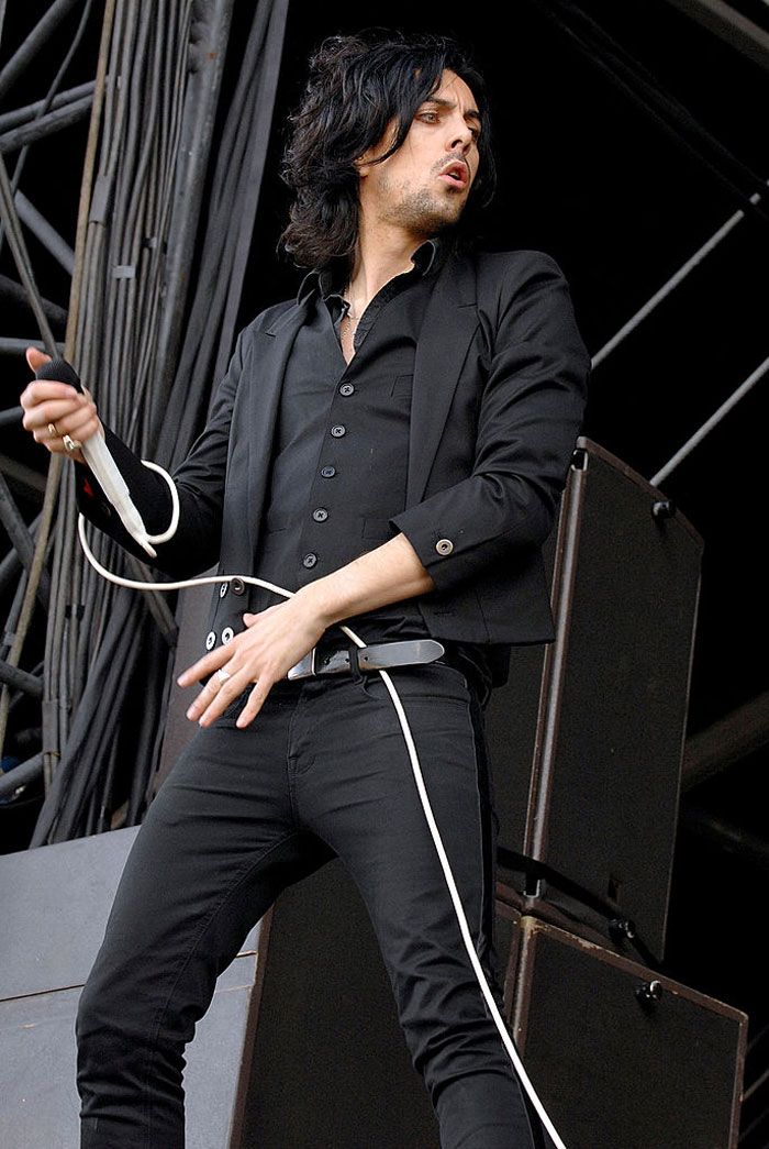 Estrella de rock actuando en el escenario con micrófono, relacionada con el ataque a prisión y el caso de crímenes contra niños.