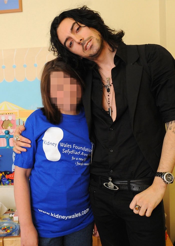 Estrella de rock posando con un joven fan en el interior con una camiseta azul de la Kidney Wales Foundation.