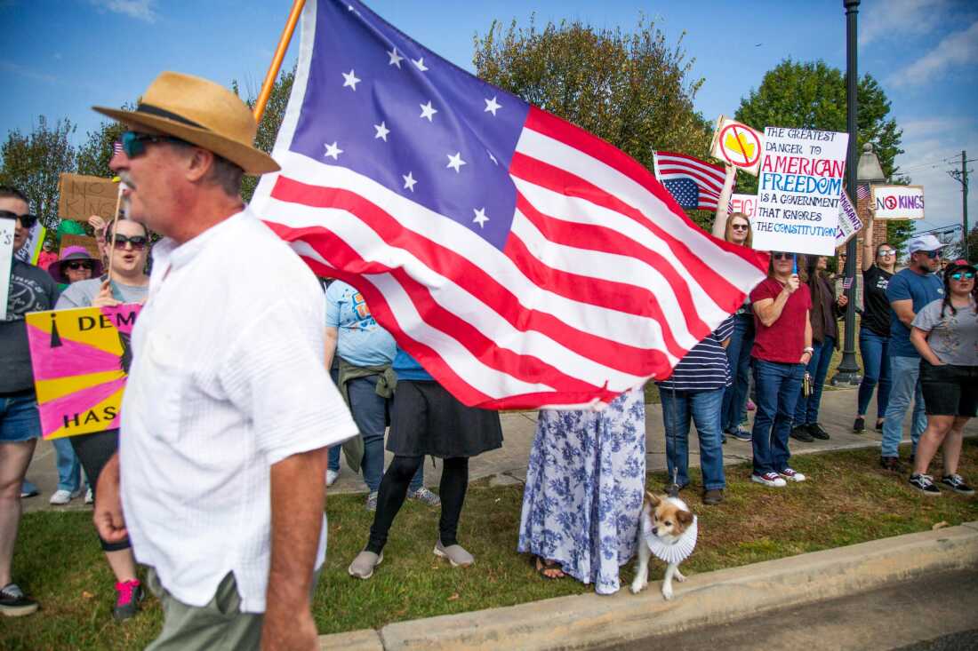 Joe Bondulich lleva una bandera entre la multitud reunida al lado de College Street en Macon, GA. 