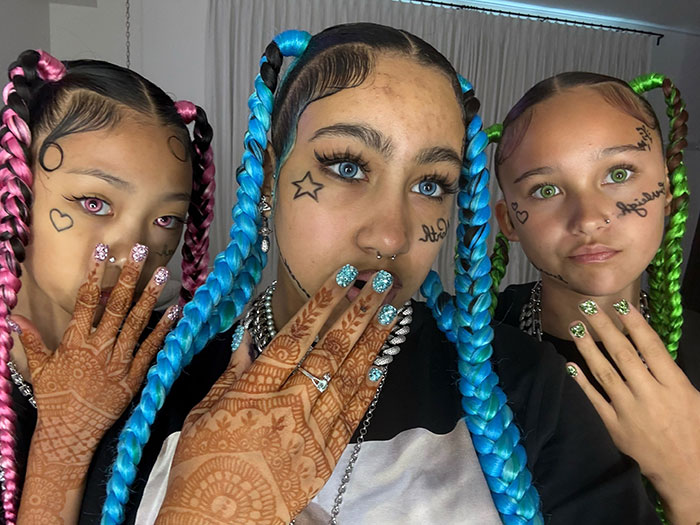 Tres mujeres jóvenes con cabello trenzado de colores y tatuajes en la cara, destacando la advertencia de Kanye West sobre la vida en línea de North.