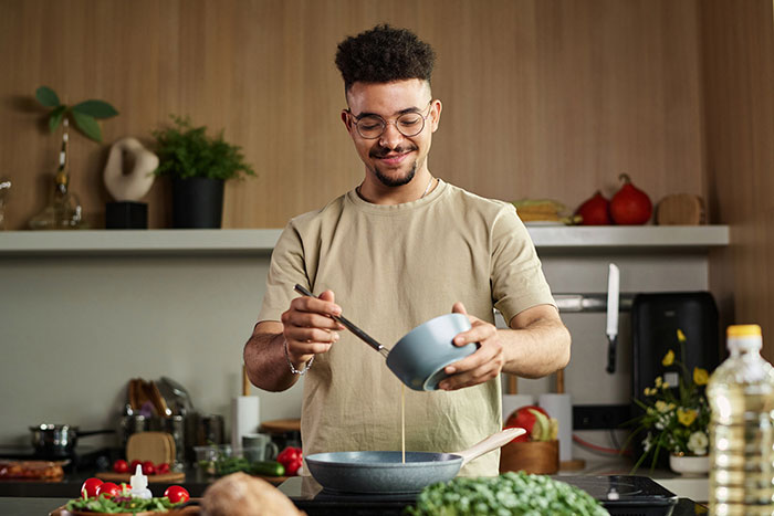 Hombre cocinando en una cocina moderna, simbolizando a una mujer que se da cuenta de que su ex podría haber estado envenenando su salud.