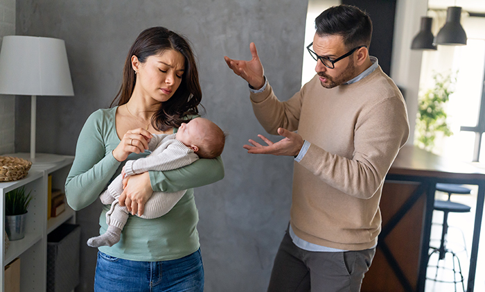 Una pareja joven en una tensa discusión después de un embarazo difícil, una mujer sosteniendo a un bebé mientras el hombre expresa frustración y resentimiento.