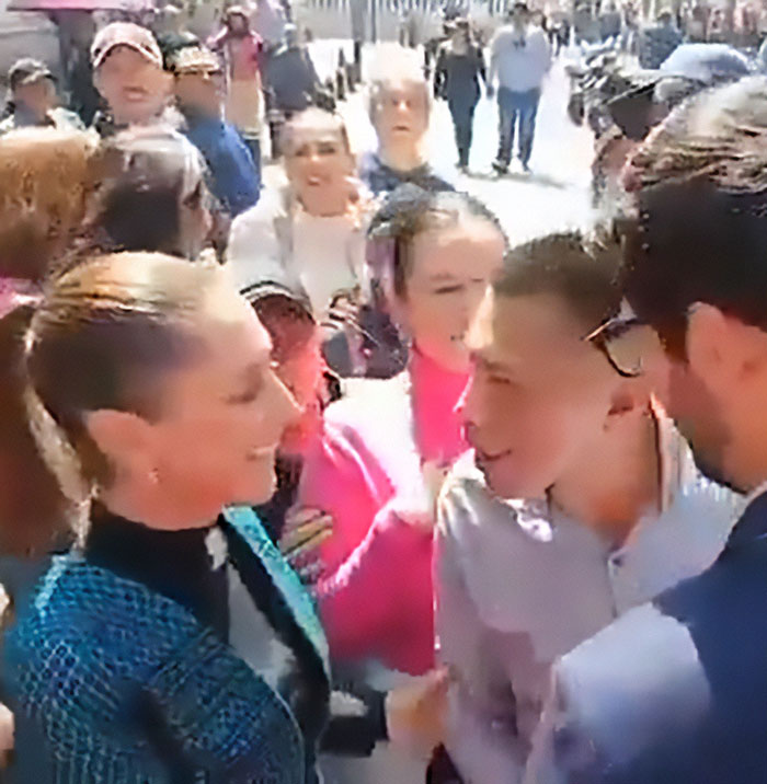 El presidente mexicano habla ante la multitud mientras un hombre la besa y acaricia en público durante el evento.