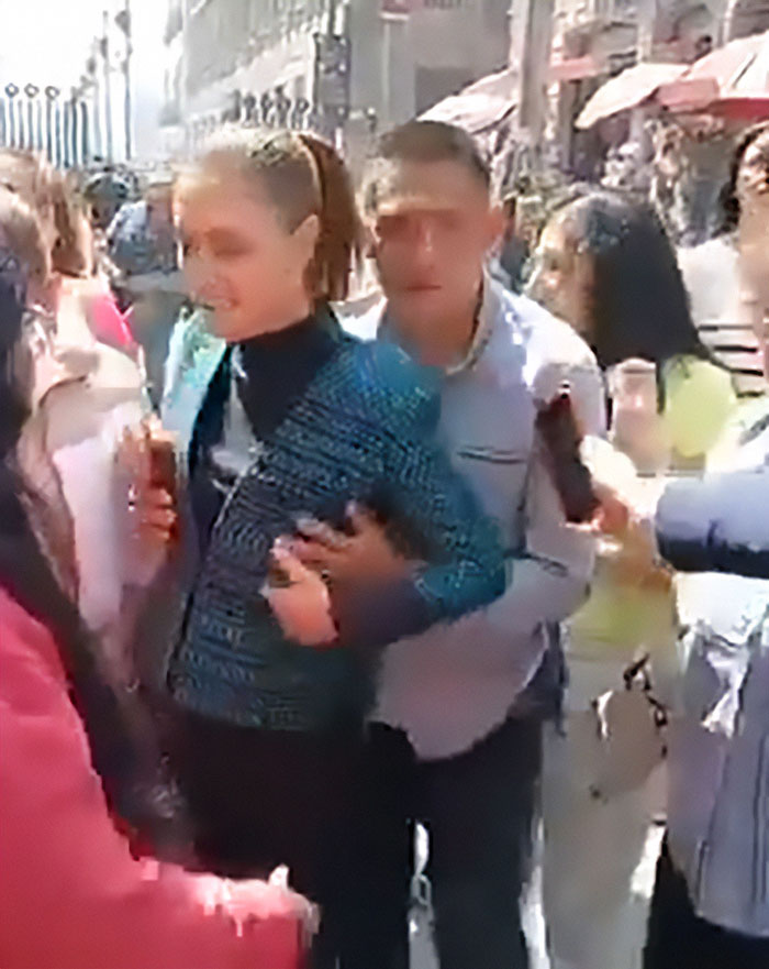 Un hombre toca a la presidenta mexicana mientras ella habla ante la multitud, resaltando la realidad de muchas mujeres en espacios públicos.