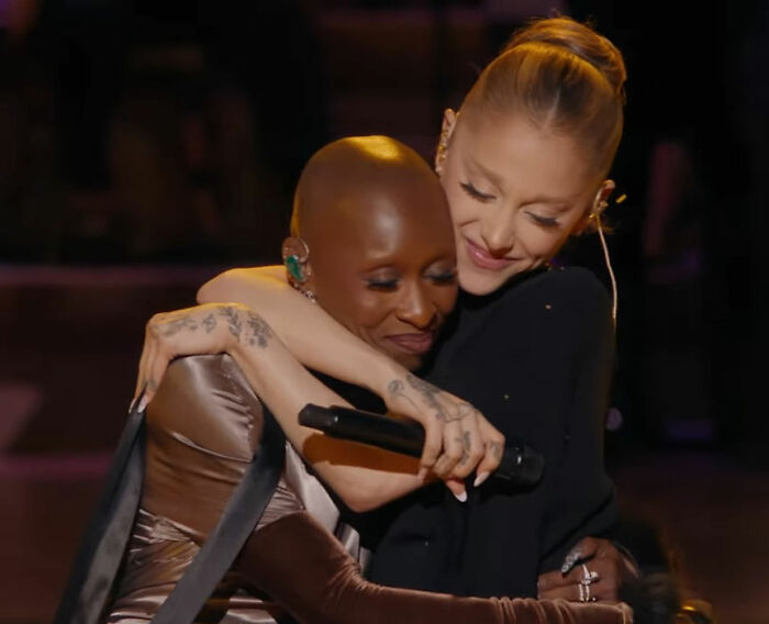 Cynthia Erivo y Ariana Grande comparten un cálido abrazo durante una presentación en vivo, mostrando su interacción única.